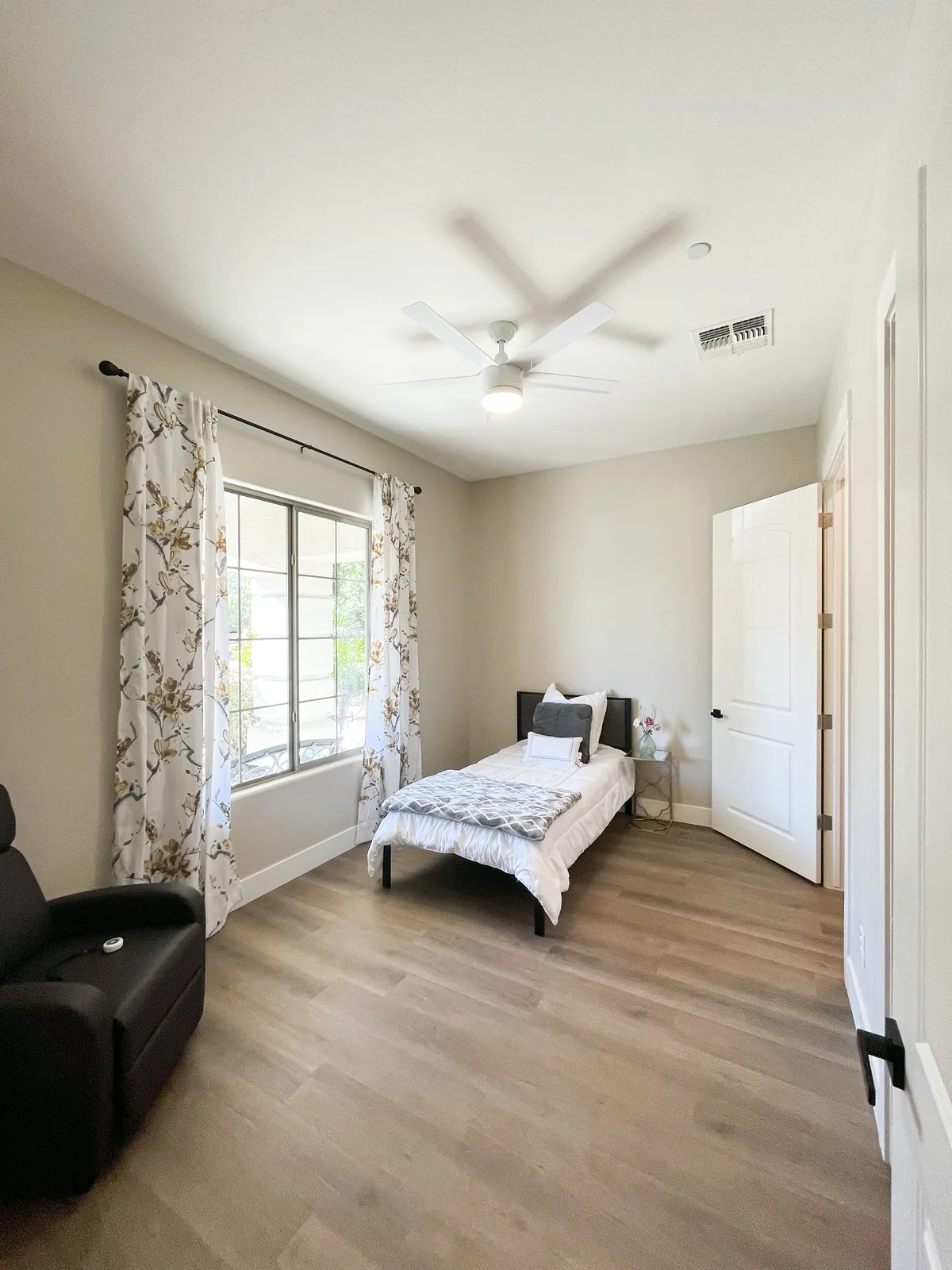 A furnished resident bedroom with soft linens and a sunny window