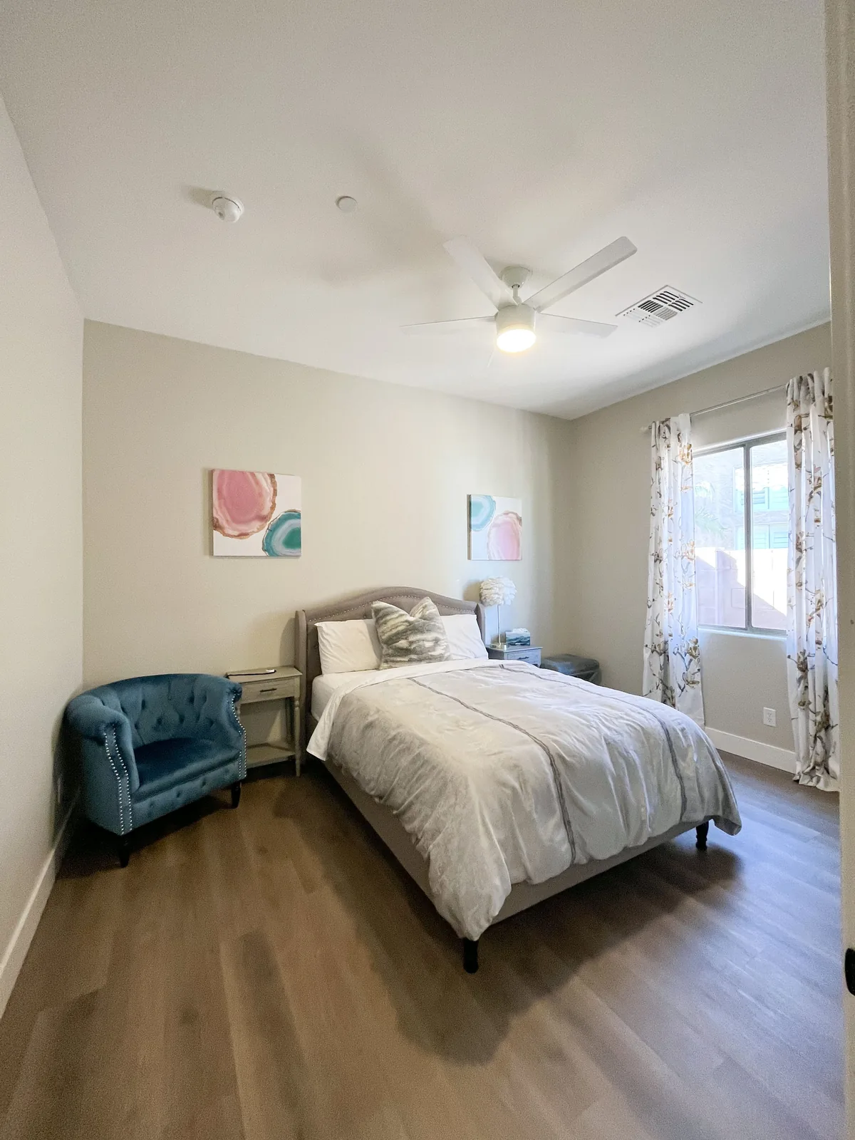 A tidy bedroom with a reading chair and natural light